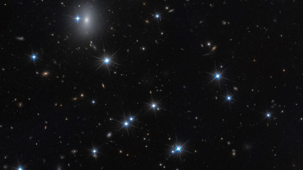 O galaxie aproape invizibilă, ascunsă într-unul dintre cele mai mari și mai interessant detailate roiuri de galaxii din Univers, a fost identificată recent cu ajutorul unor metode inovatoare